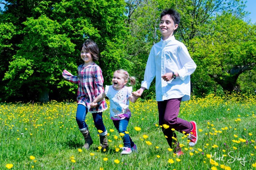 children running in a meadow - family portrait photograph - Mark Sisley Photography