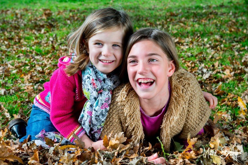 young girls laughing in autumn leaves - family portrait photograph - Mark Sisley Photography