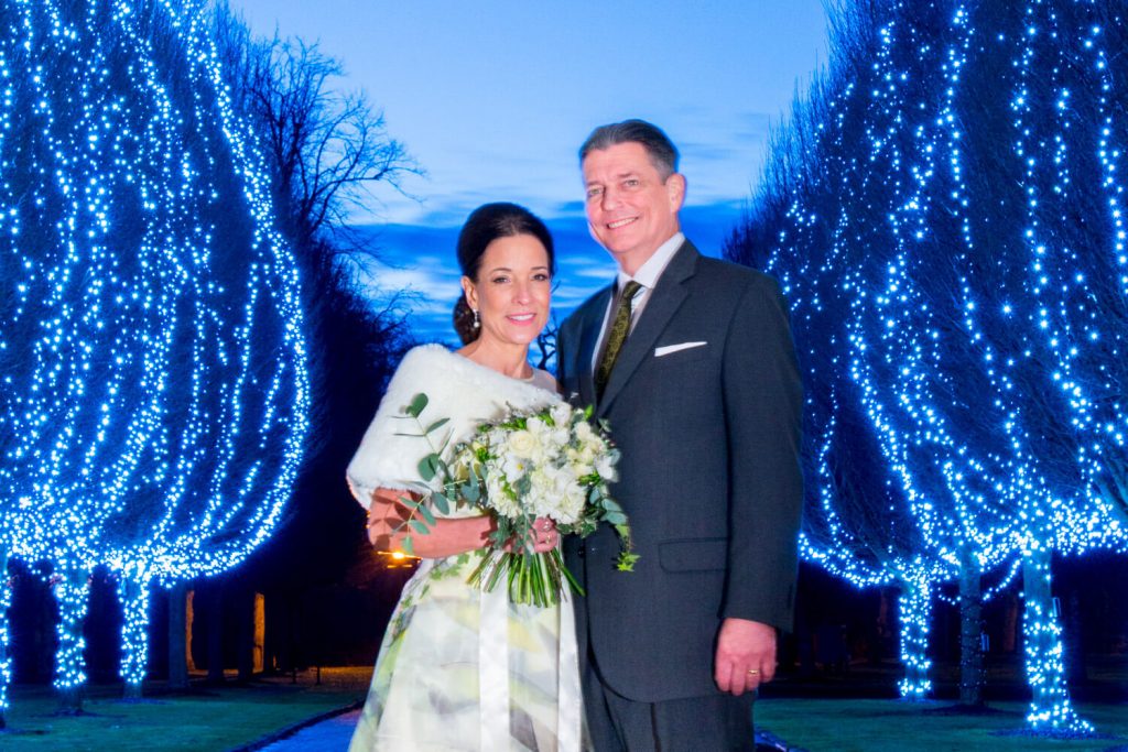 Danesfield House winter wedding photography of the newlyweds with the illuminated tree aisle at the entrance