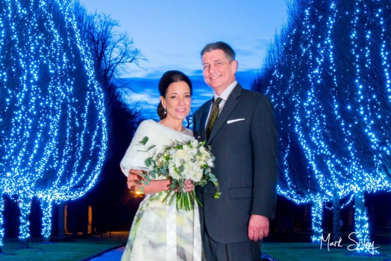 Danesfield House winter wedding photography of the newlyweds with the illuminated tree aisle at the entrance