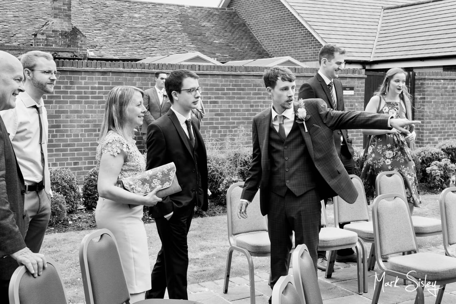 Natural photography of the groom as he guides his guests to their seats - Lambert Hotel wedding near Thame