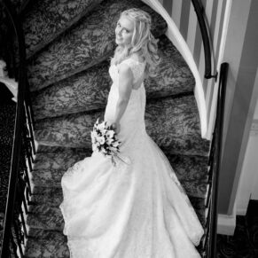 Black and white image of bride on staircase at Beaumont House wedding