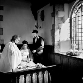 Black and white image of bride and groom signing the register at Dorton House chapel wedding ceremony