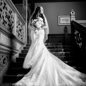Black and white image of bride on staircase at her Eynsham Hall wedding