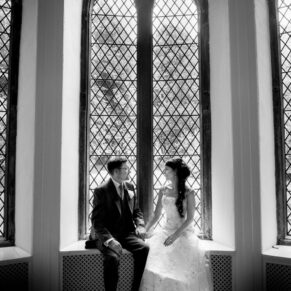 Window-lit black and white image of bride and groom at Clearwell Castle wedding