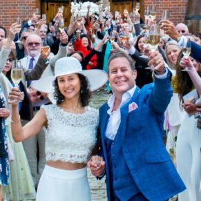 Classic wedding photography Buckinghamshire of the newlyweds with their guests at the entrance to The Dairy, Waddesdon