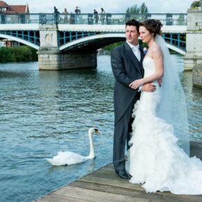 Photography of bride and groom watching swans on river Thames at Sir Christopher Wren House Hotel Windsor wedding