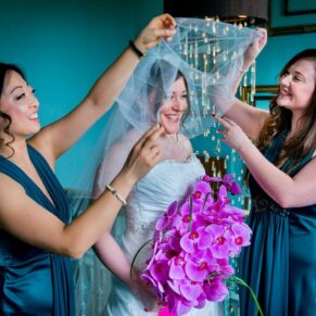 Photography of bride with bridesmaids fixing her veil at Stoke Place wedding