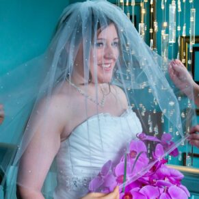 Window-lit portrait of bride with orchids at Stoke Place wedding