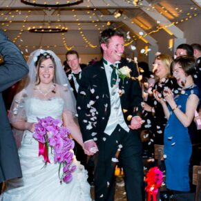 Bride and groom walking through confetti aisle at Stoke Place wedding