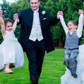 Photography of bride and groom swing their children at Taplow House Hotel wedding