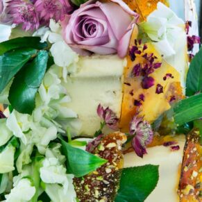 Close-up image of wedding cake with pistachio brittle and white freesias and roses at Taplow House Hotel wedding