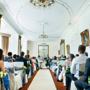 Wedding ceremony at Taplow House Hotel with white chair covers and grey sashes