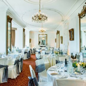Taplow House Hotel wedding breakfast with round tables and white chair covers with pewter grey sashes