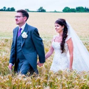 Bride and Groom walking through wheat field - wedding at Clearwell Castle