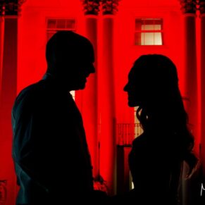 The newlyweds in silhouette at the front of the floodlit red house