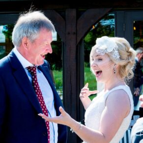 Brocket Hall wedding photographs of the bride giggling with a fiend on the terrace at the golf club