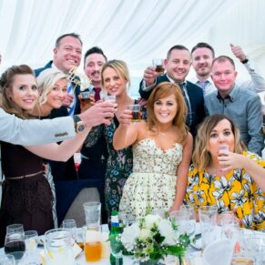Summer's day group pose of some wedding guests inside the marquee at Missenden Abbey