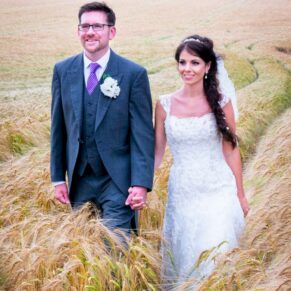 Clearwell Castle wedding shot of the newlyweds strolling in the wheat field