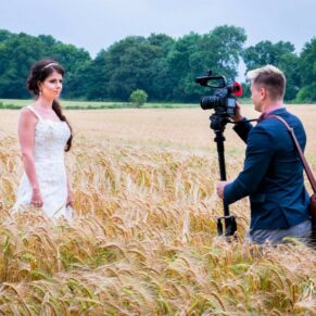 Clearwell Castle wedding image of the bride being filmed in a wheat field