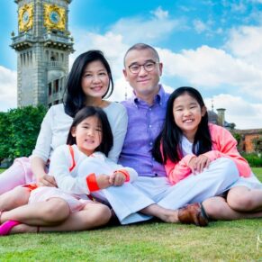 Cliveden House Buckinghamshire portrait photography of a family sat on the ground with the clocktower behind