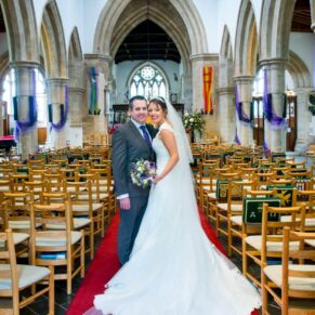 Wedding at St Mary's Church Thame - the bride and groom pose for the camera with the stunning interiors behind them