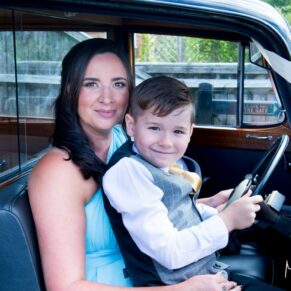 Little boy and bridesmaid in vintage wedding car at Notley Tythe Barn wedding