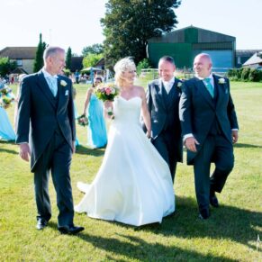 The newlyweds walk with the ushers at Notley Tythe Barn wedding