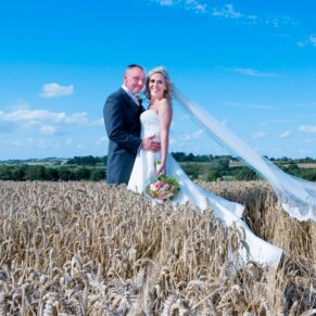 Bride navigating through the wheat meadow at her Notley Tythe Barn wedding