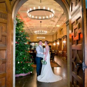 The newlyweds through the archway at Eynsham Hall Christmas wedding