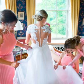 Hartwell House wedding photographs of the bridesmaids arranging the bride's gown