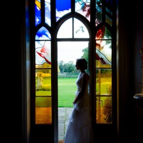 Missenden Abbey wedding pictures of the bride beside the stained glass window