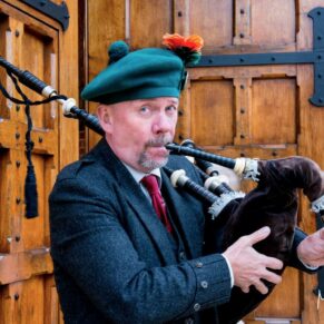 Waddesdon Dairy winter wedding photography of the bagpiper at the front doorway to the venue