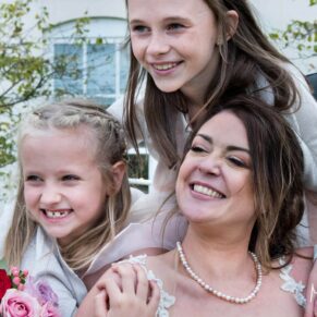Photography of the bridesmaids giving a big hug to the bride at the front of Sopwell House Hotel on her wedding day