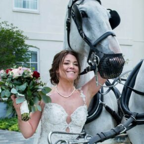 Photography of the bride posing for a picture at the front of the house with her fabulous horses after her carriage ride through the local countryside to Sopwell House Hotel