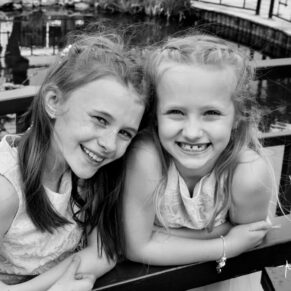 Photography of two smiling flower girls in the gardens at this Sopwell House summer wedding