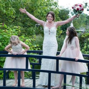 Photography of the happy bride messing about on the bridge at Sopwell House with her two gorgeous wedding flower girls