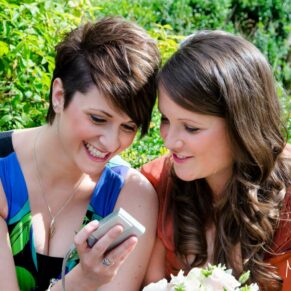 Two ladies enjoying some online banter with a friend who's not at the wedding