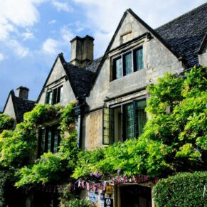 The Bay Tree Hotel's honey coloured historic Cotswold stone exterior is adorned with a climbing wisteria plant for this wedding photography shot
