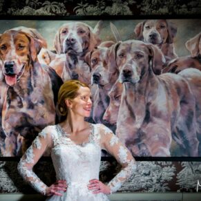 Photography of the bride as she poses besides a large painting for a dramatic classic portrait at her Bay Tree Hotel wedding in Burford