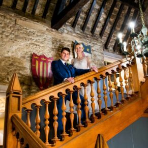 Photography of the bride & groom as they strike a pose on the grand old staircase at their Bay Tree Hotel wedding in Burford
