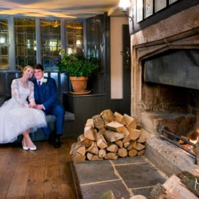 Photography of the newlyweds by the open fire inside the fabulous Bay Tree Hotel in Burford on their wedding day