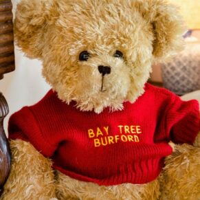 Photography of teddy bear wearing the hotel's name captured in the bridal suite at The Bay Tree in Burford