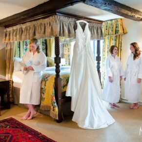 Photography of the bride sat on the bed reading a card from her future husband in the bridal suite pre ceremony at her Bay Tree Hotel wedding in Burford