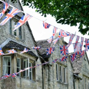 Photography of colourful union jack bunting blowing in the wind outside this Bay Tree Hotel wedding in Burford