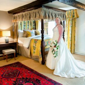 Photography of the bride in her grand bridal suite next to the fabulous four poster bed at her Bay Tree Hotel wedding in Burford