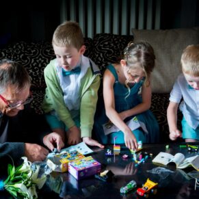 Photography of the children playing a board game and lit with atmospheric window lighting during the drinks reception at this Beaumont Estate wedding