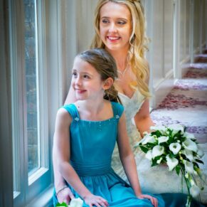 Photography of the bride with her bridesmaid sat on the ground inside the Beaumont Estate's historic passageway on her wedding day