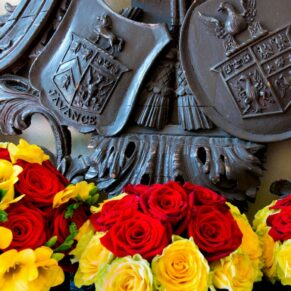 The wedding bouquets placed on an antique highly detailed dark oak pew at Bisham Abbey