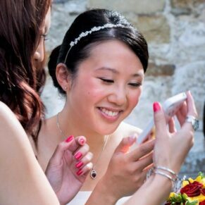 Candid wedding photography of the bride looking at a friend's phone during the drinks reception